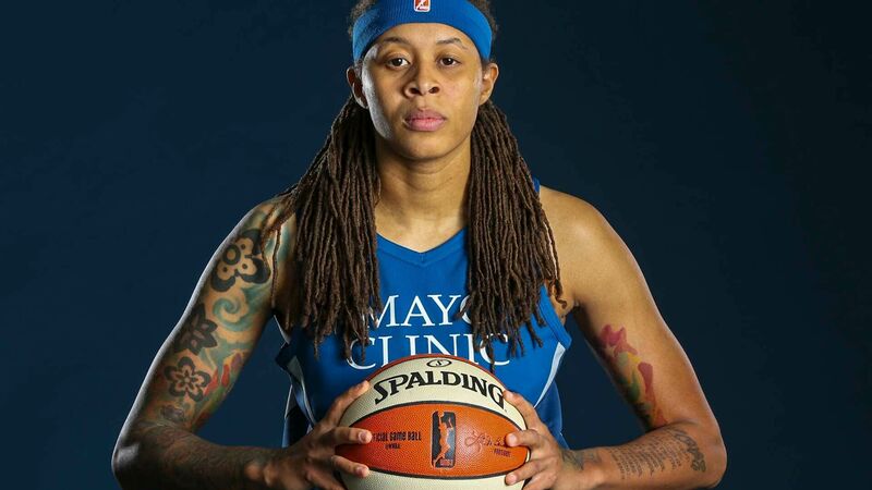 Seimone Augustus poses for a photo as a member of the WNBA's Minnesota Lynx. she is holding a basketball with both hands at chest level.